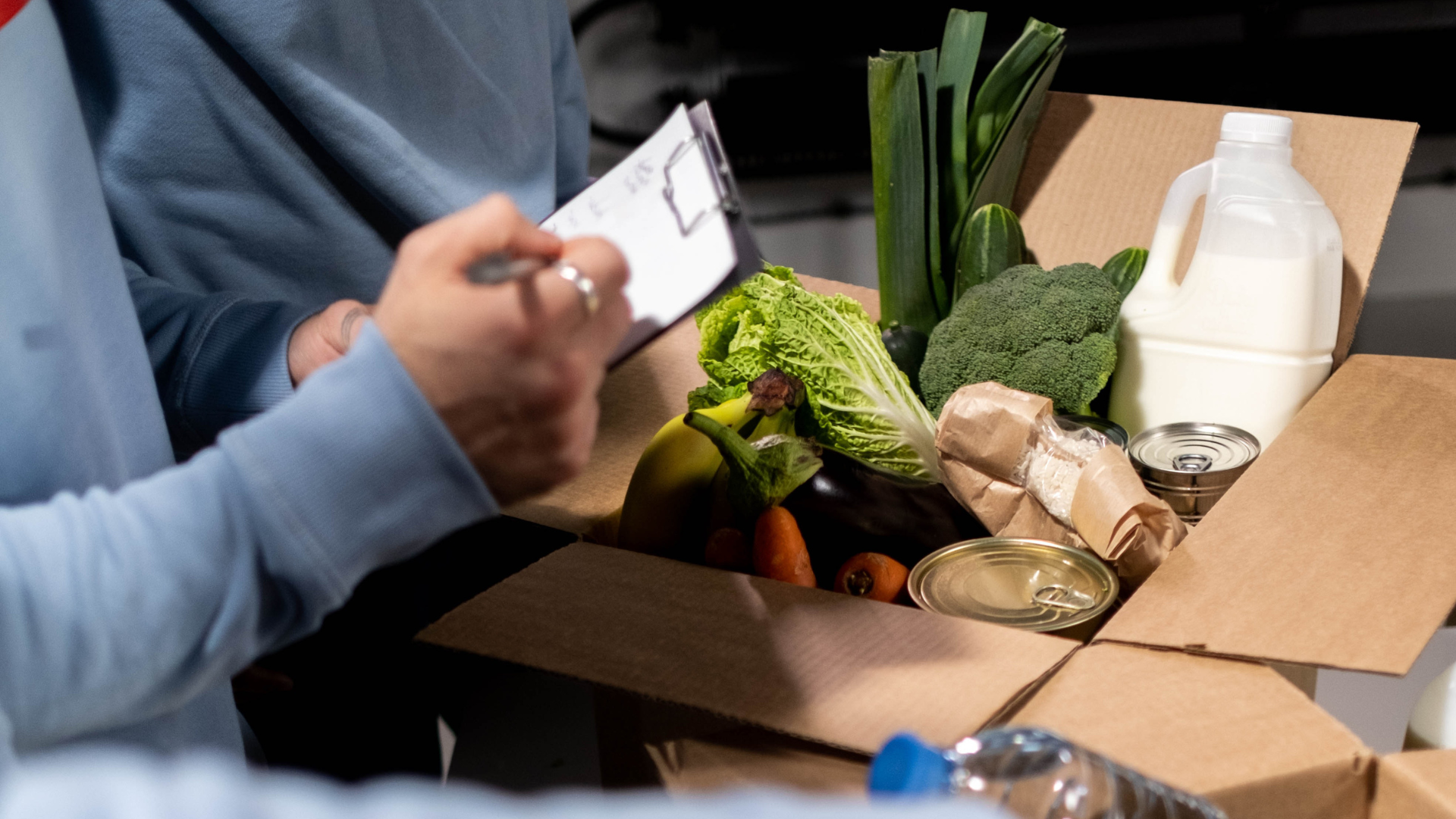 A person is writing in a box filled with vegetables.