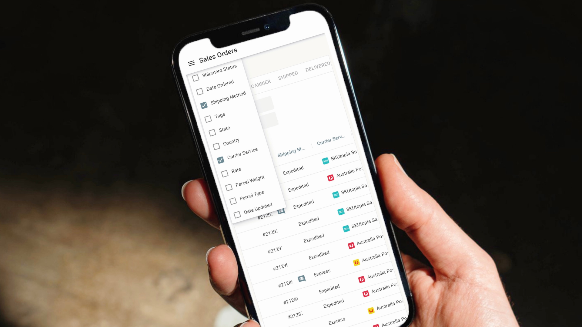 A hand holding a phone with a screen displaying a list of orders.
