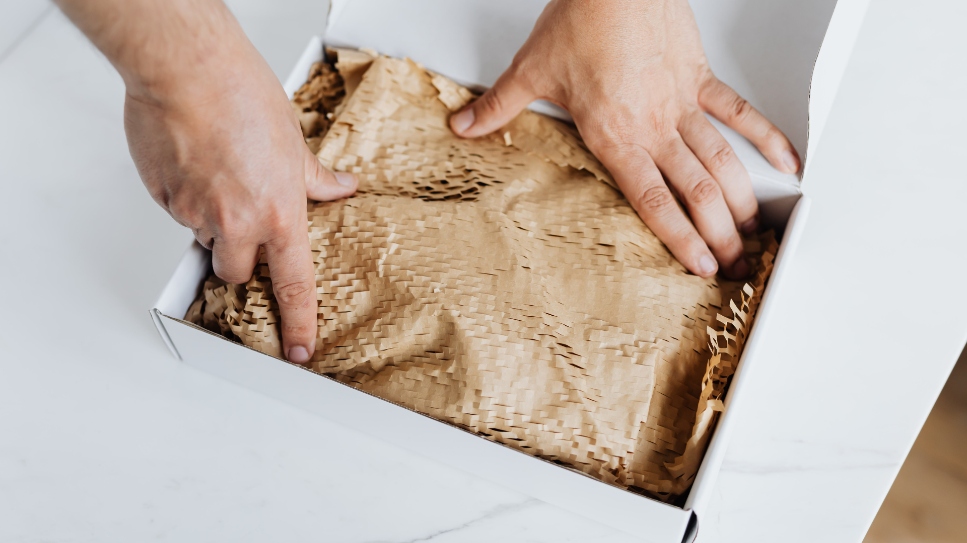 A person is holding a box with a brown paper inside.
