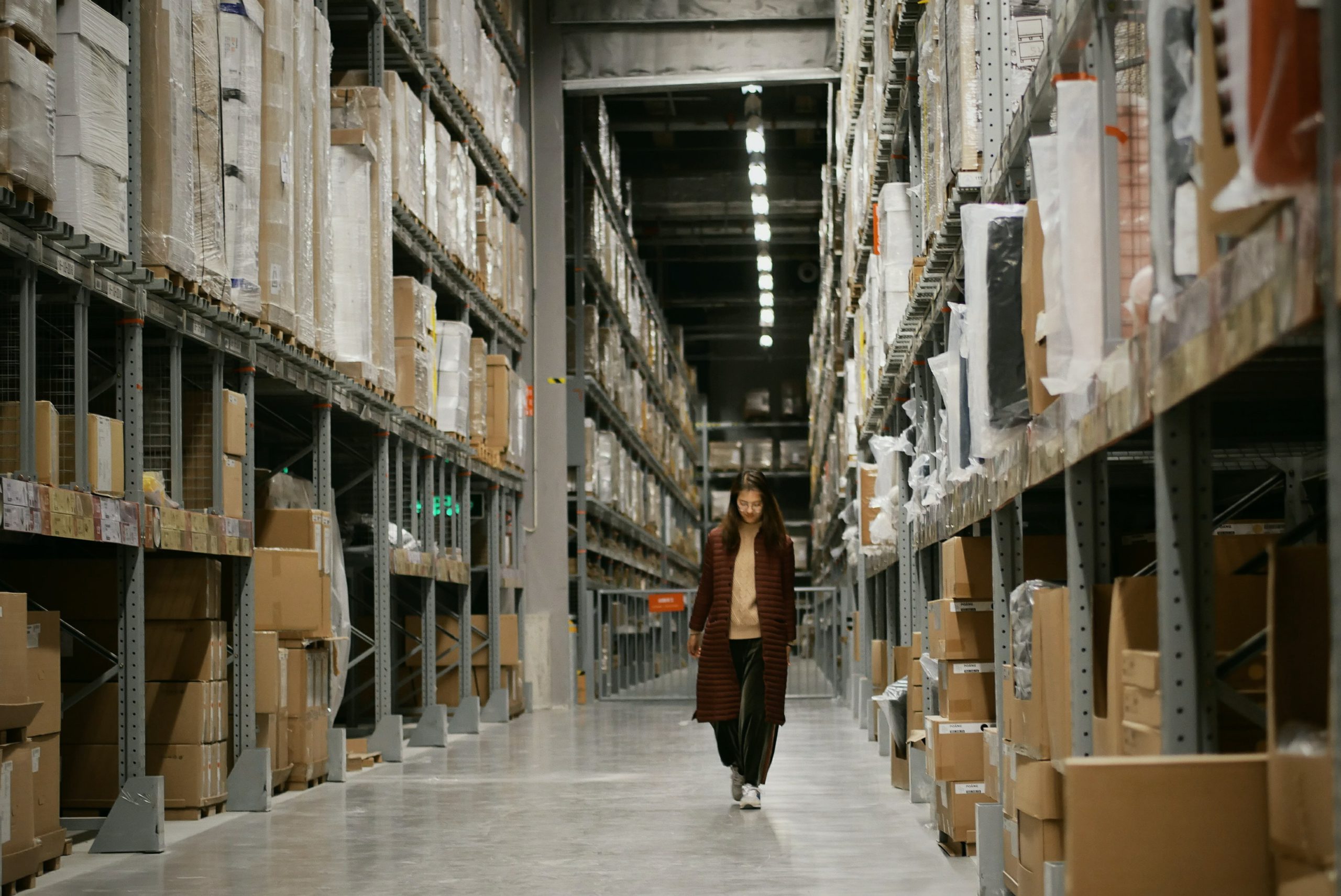 A woman walking through a warehouse with boxes.
