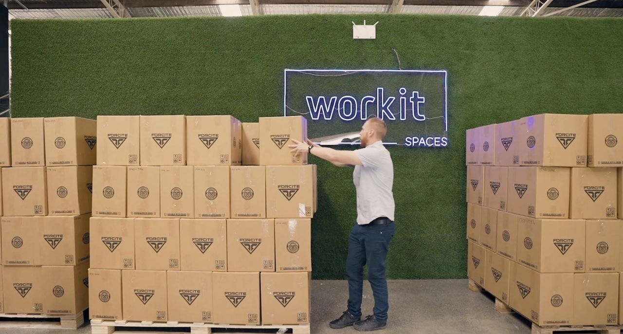 A man is standing in front of a stack of brown boxes.