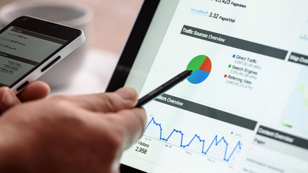 A hand is pointing at a pie chart on a tablet.