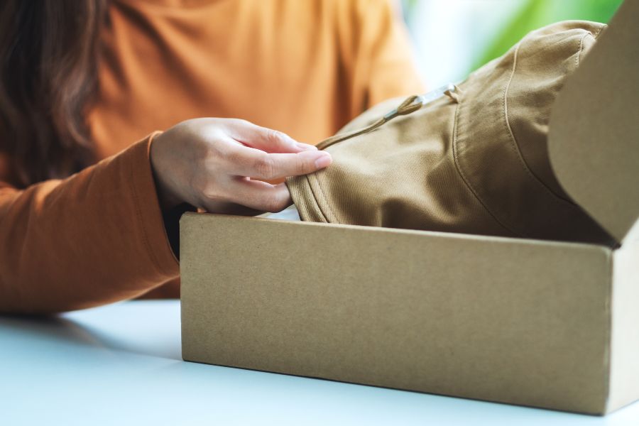 Woman opening a clothing return package, illustrating the RMA process explained.