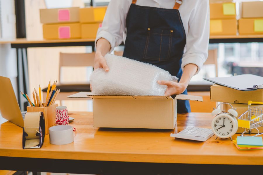 Small business owner packing an order with bubble wrap, representing key DTC fulfilment steps.