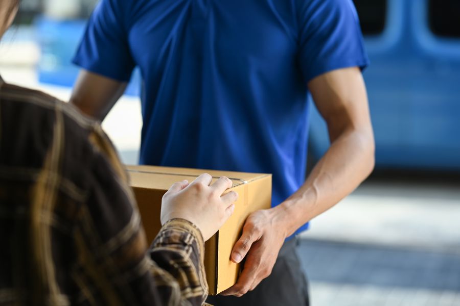 Close-up of a delivery handoff, showing a parcel exchange between courier and customer.