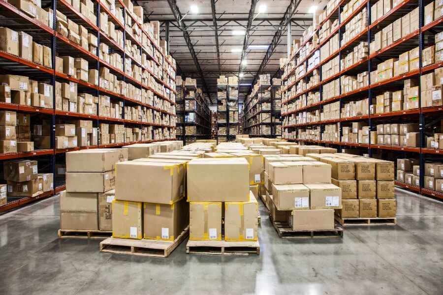 Large warehouse filled with stacked boxes and shelves, representing logistics challenges and solutions.