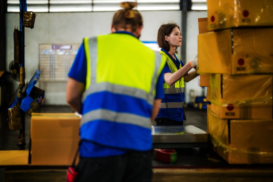Warehouse staff coordinating and handling packed boxes for efficient and cost-effective business shipping operations.