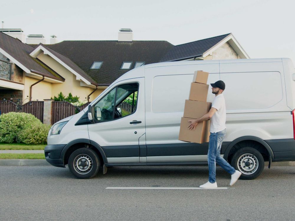 A man is walking down the street carrying a box.