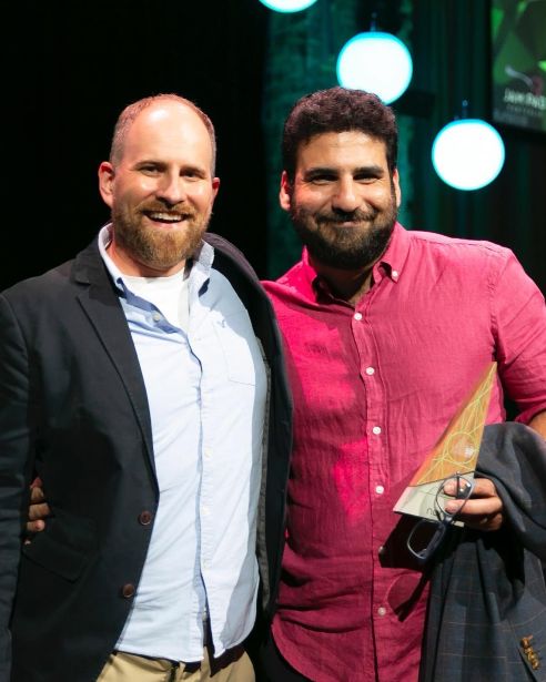 Two men posing for a picture with one holding a trophy.