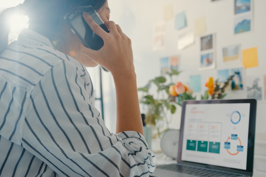 Businesswoman on phone using laptop to check logistics data for 3PL customer support