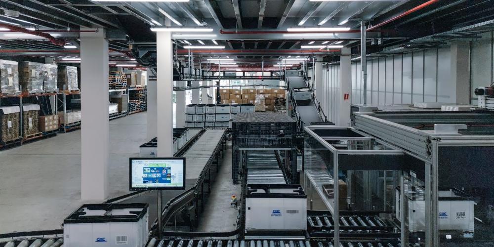 A large warehouse with a conveyor belt and a computer screen.