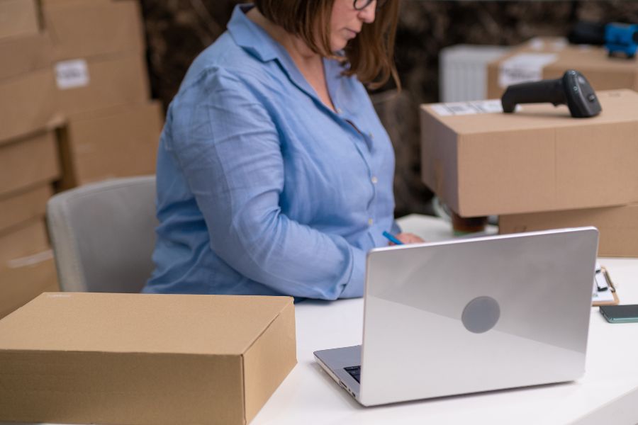 Woman managing boxes and inventory on a laptop while planning backorders and stock levels