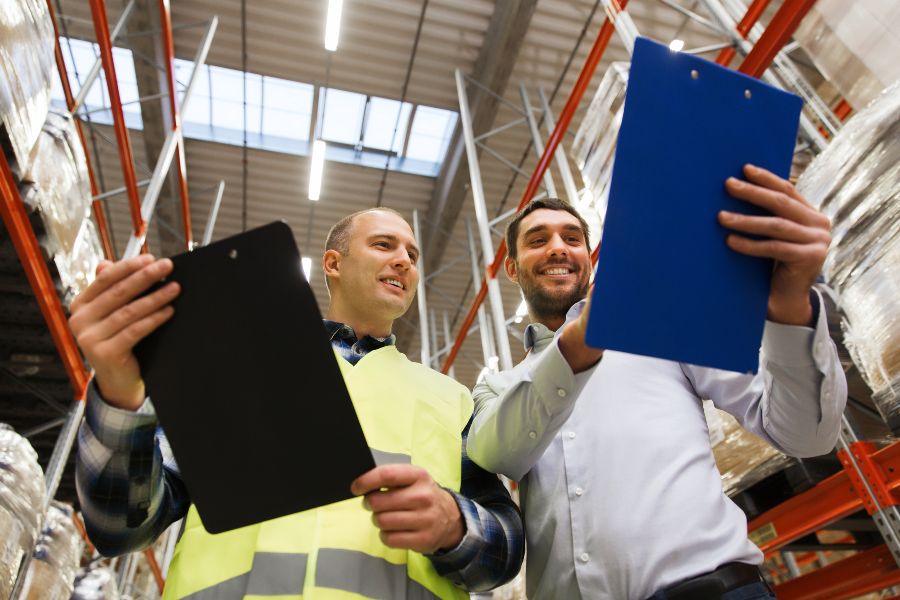 Workers reviewing clipboards in a warehouse to represent collaboration between logistics providers