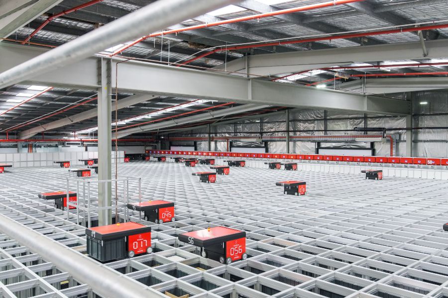 A large warehouse with many red boxes and a metal railing.