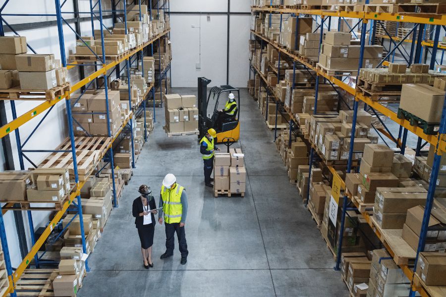 A woman in a black dress and a man in a yellow vest are standing in front of a box.