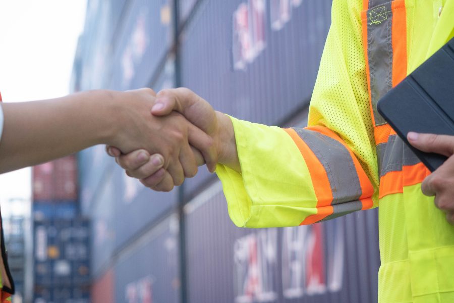 A man in a yellow safety vest shakes hands with another man.