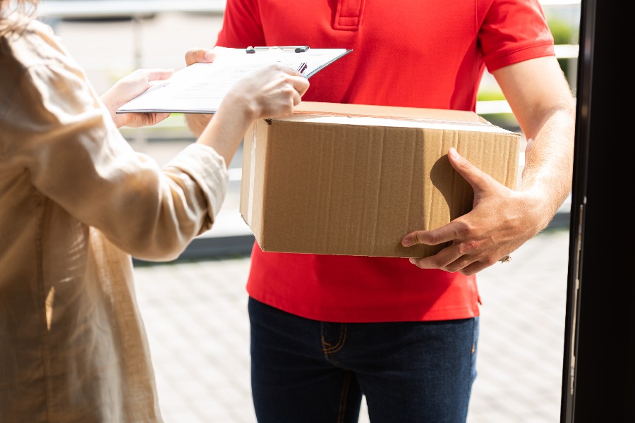 A man in a red shirt is holding a box.