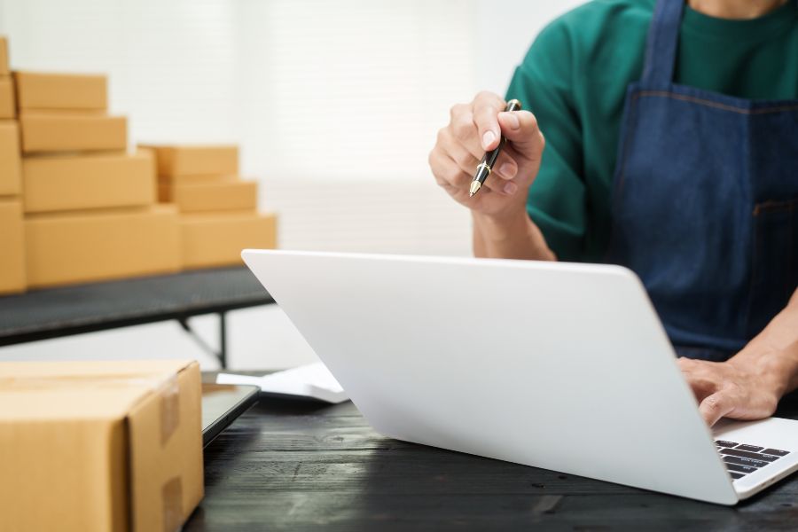 Person working on laptop beside packed boxes