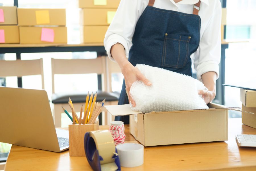 A woman holding a box with a white tape on it.