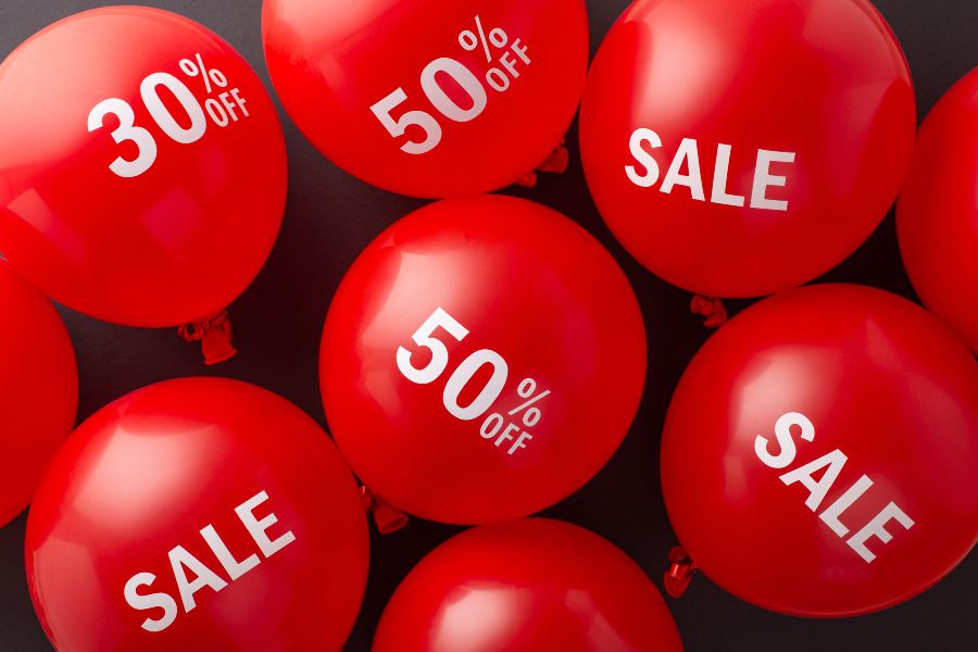 A bunch of red balloons with the word sale written on them.