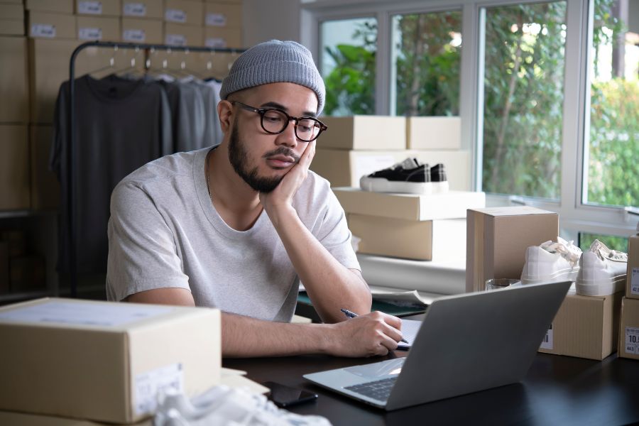 A man in a white shirt is working on a laptop.