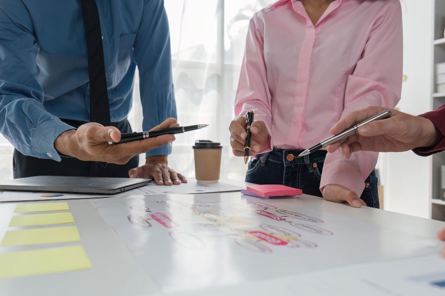 Team reviewing brand strategy notes together around a table covered with diagrams and sticky notes.