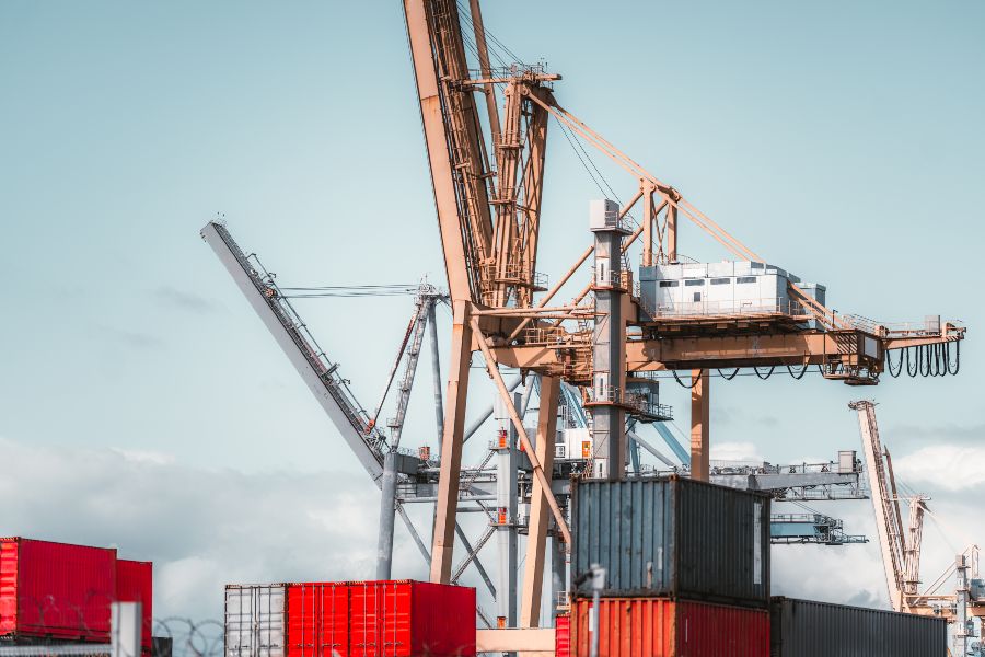 Shipping containers stacked at an Australian port with large cranes used for import and export logistics.