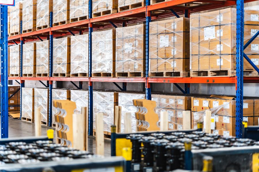 Warehouse shelves stacked with wrapped boxes in a busy storage aisle.