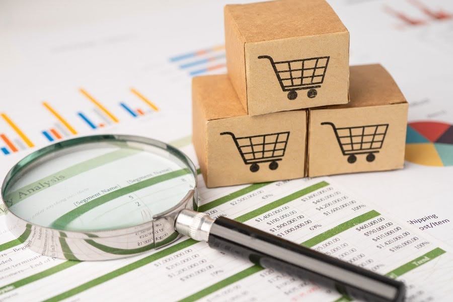 Magnifying glass over ecommerce charts and shipping cost analysis boxes.