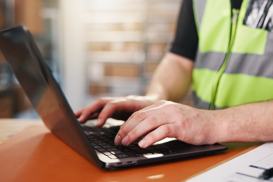 Warehouse worker using a laptop in a depot.