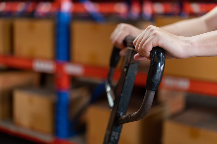 Close-up of a staff worker pushing a trolley in a warehouse.