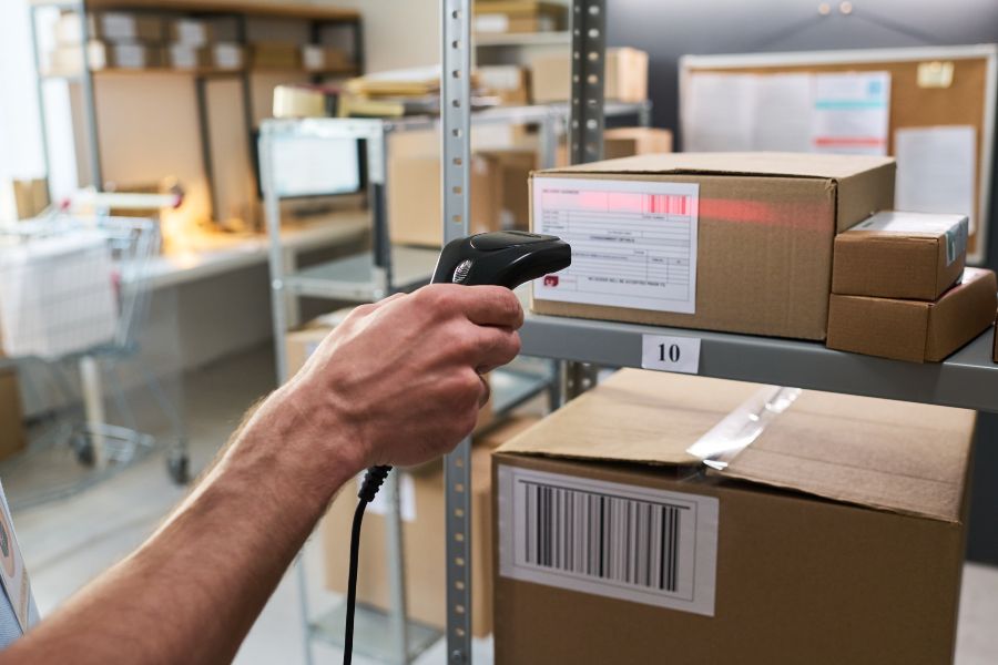 Worker scanning parcel barcode with RF scanner to reduce picking errors in fulfilment centre
