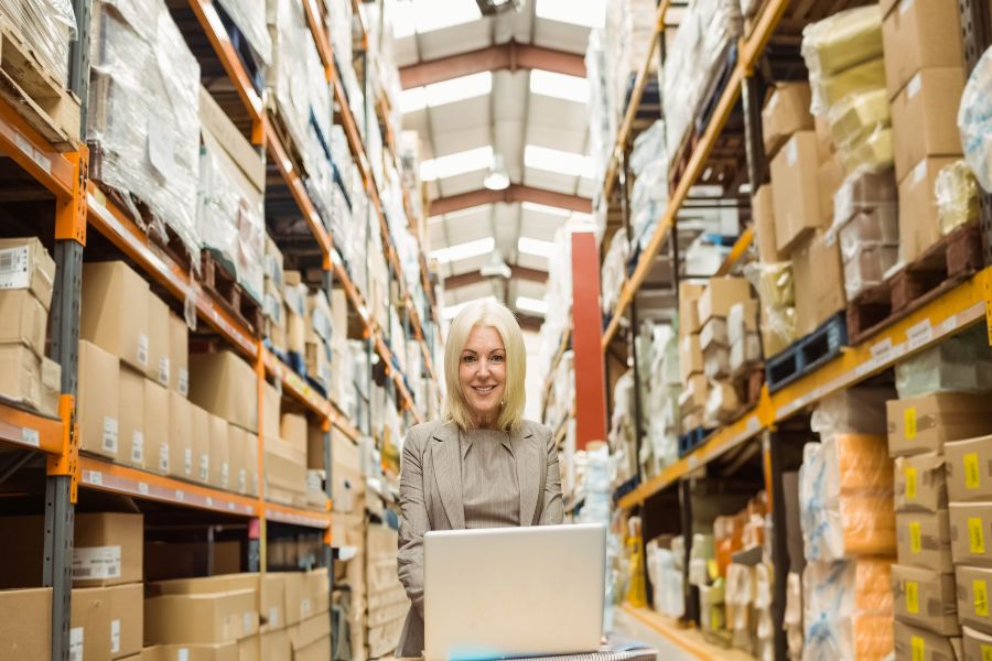 Warehouse manager using laptop for stock control in ecommerce distribution centre