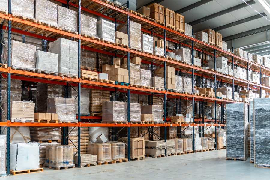  Warehouse shelves filled with boxes and pallets, illustrating storage space that dead stock can occupy.