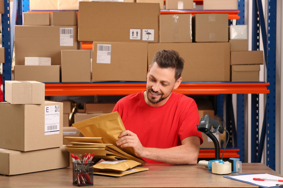 Warehouse worker preparing packages beside stored inventory, illustrating stock handling and dead stock management.