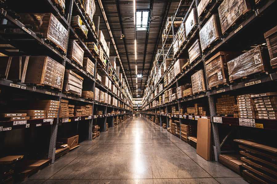 warehouse aisle with tall shelving stacked with boxes, illustrating safety stock levels without tying up excess cash