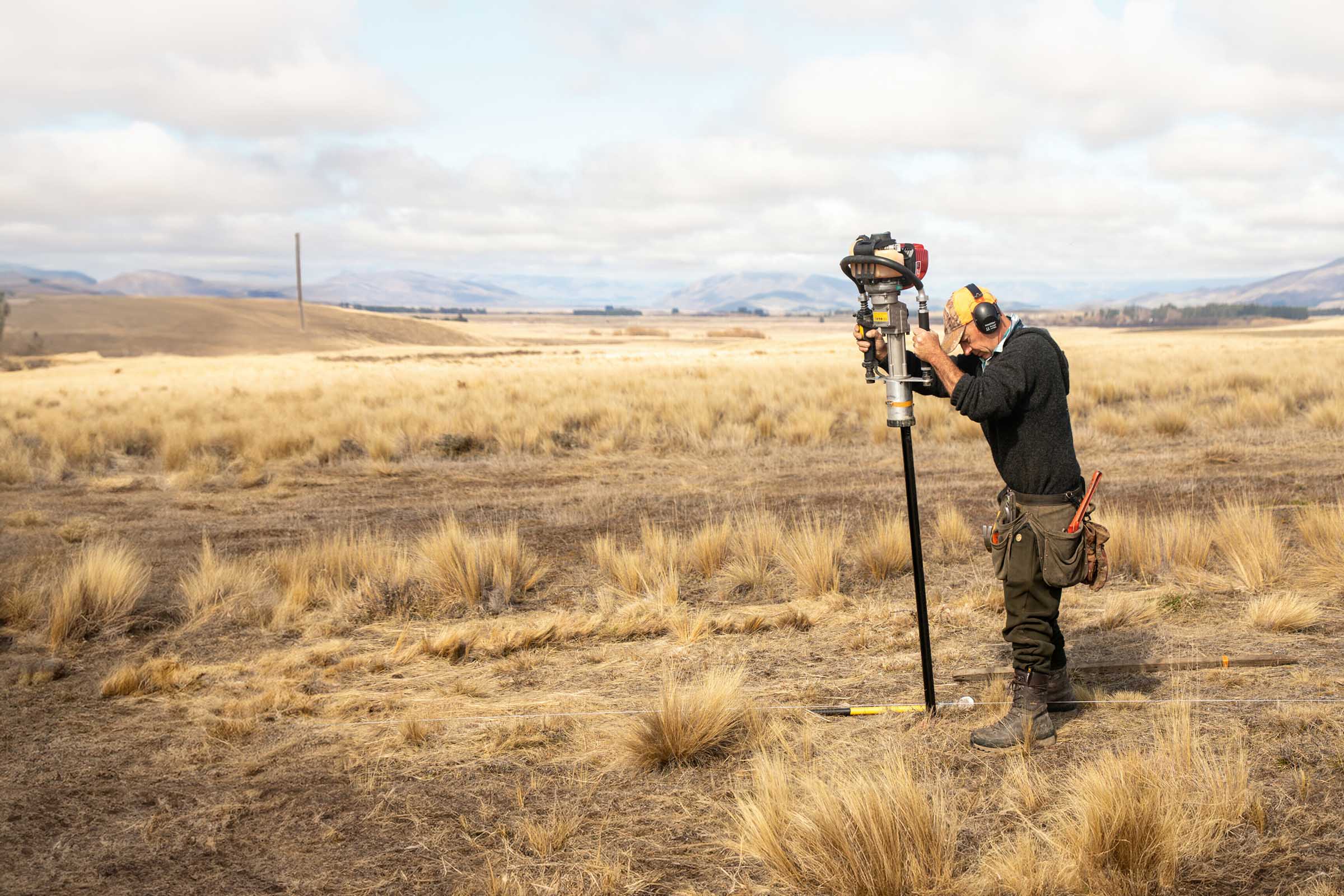 A man drilling wholes for fencing wearing hearing protection who might qualify for ACC funded hearing aids