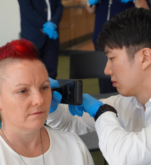 Resonate Audiologist, Min performs an earwax removal process on audiologist, Gemma, during a certification training programme.