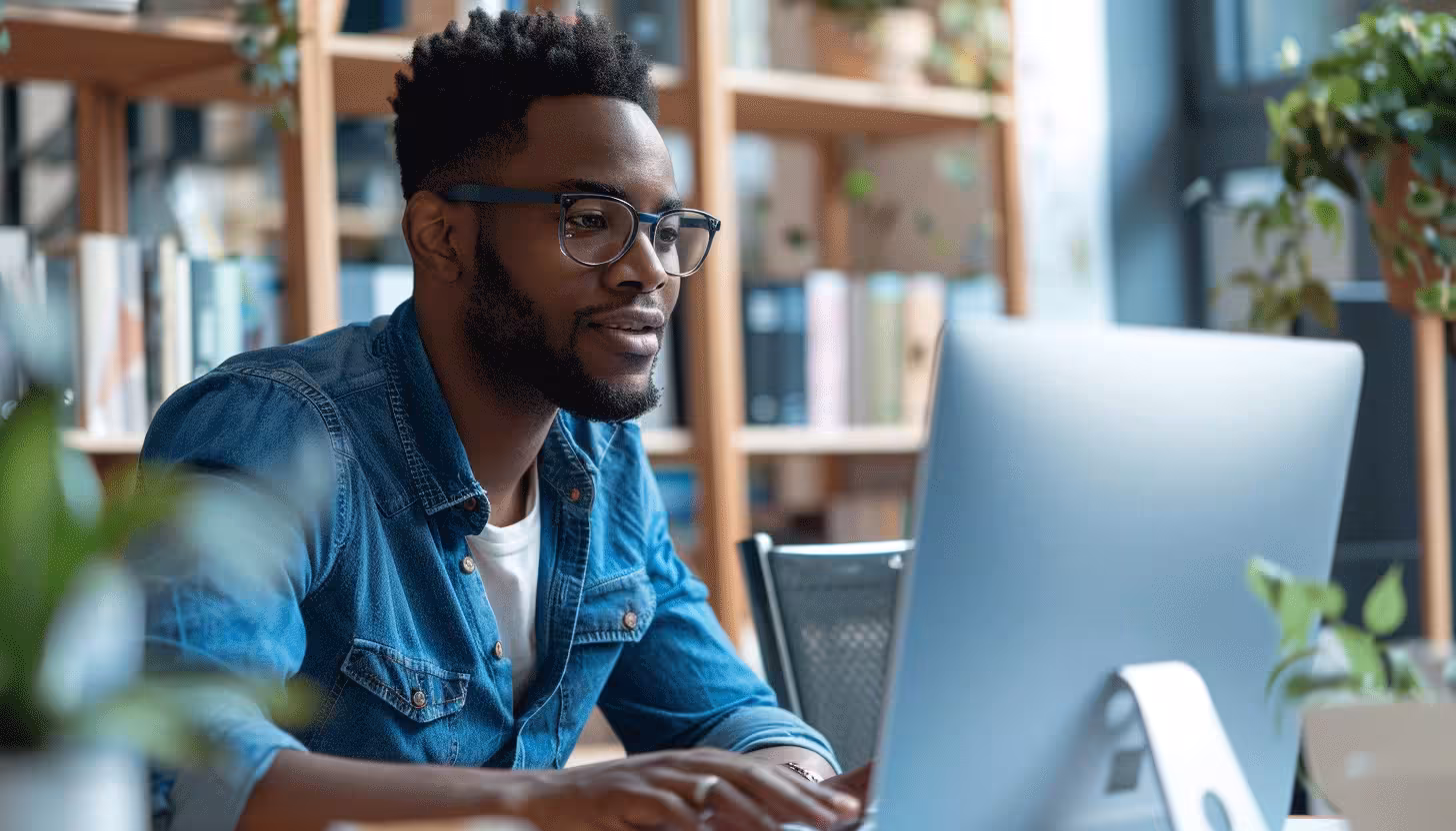 Marketo and Opensense integration playbook cover image - Man wearing glasses and a denim shirt works on a desktop computer in a bright, modern office