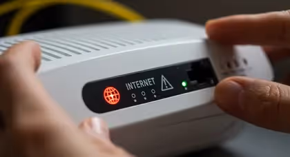 Mãos segurando modem com alerta vermelho de internet