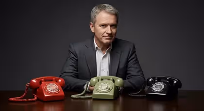 Homem com três telefones antigos sobre a mesa