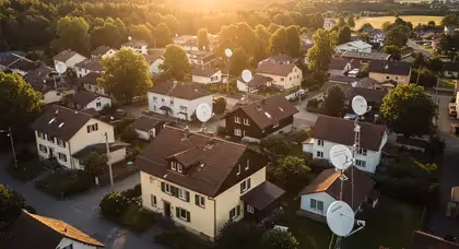 Casas em bairro residencial com antenas parabólicas ao entardecer.