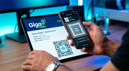 Smartphone escaneando QR Code de fatura digital da Giga+ Fibra em um tablet para pagamento via PIX.