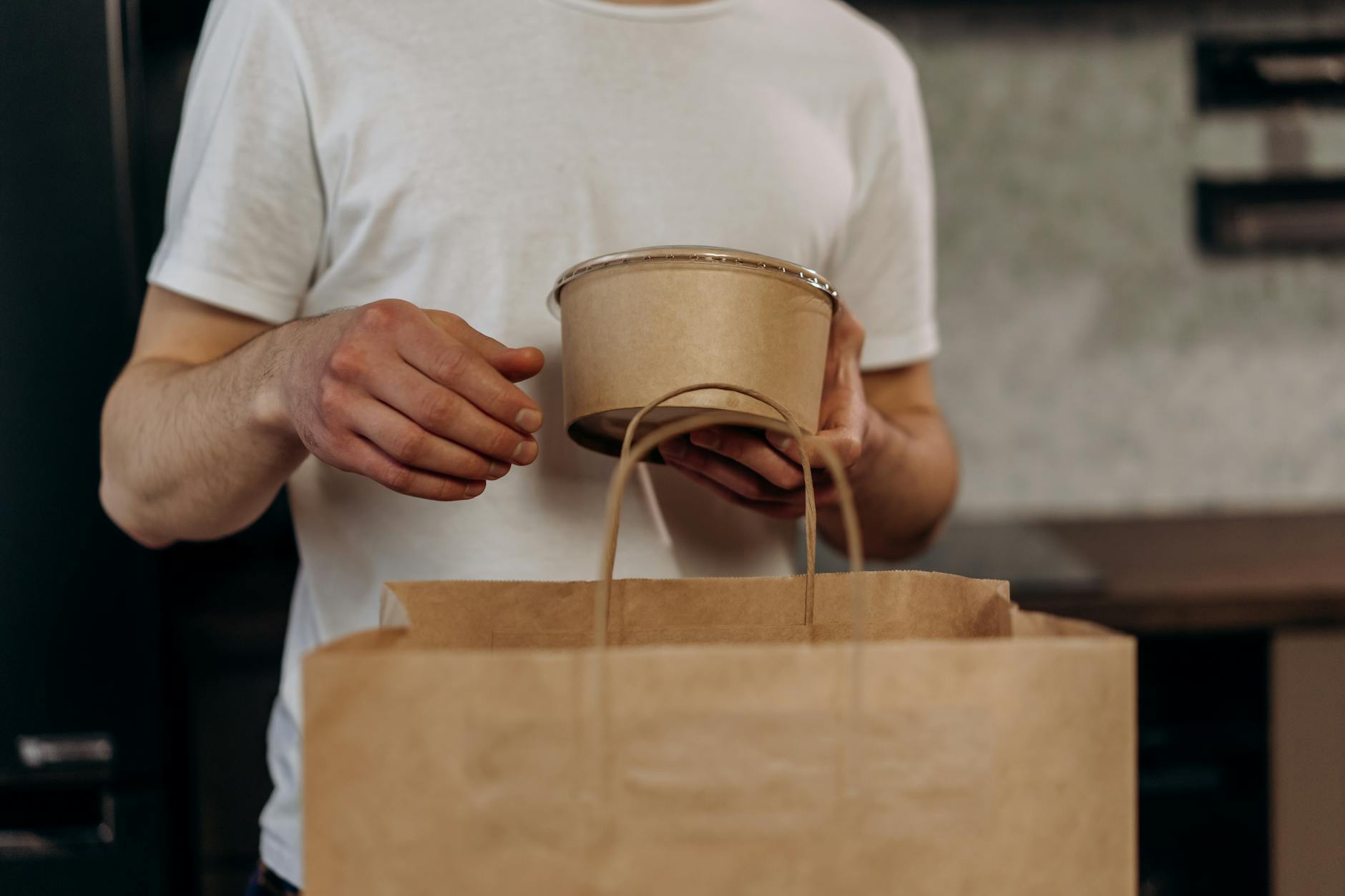 Close-up of certified compostable food packaging with BPI certification logo and composting symbols clearly visible on brown kraft paper packaging