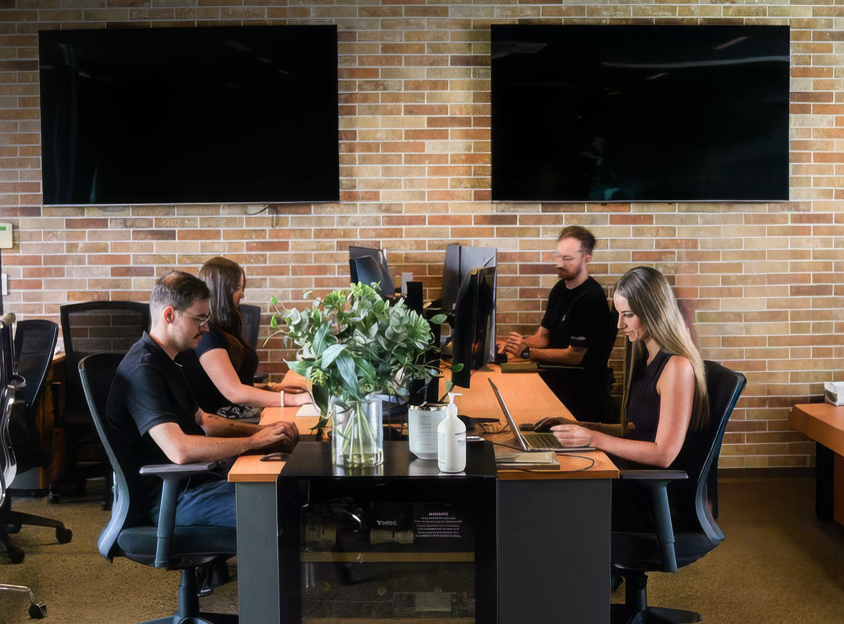 Gallery team members working together at a shared desk in the office