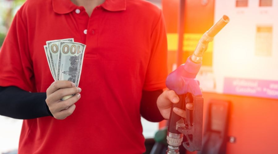 man holding a fuel nozzle and 100 dollar bills