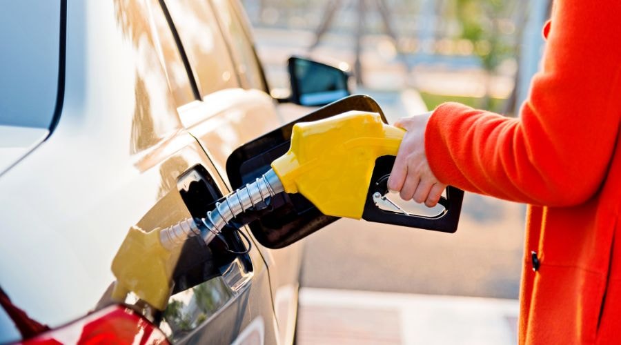Person refueling a car with a yellow gas pump nozzle
