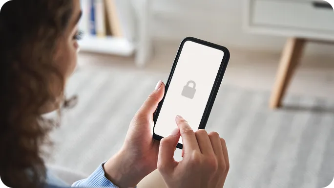 Person holding a smartphone displaying a lock icon on a white screen.