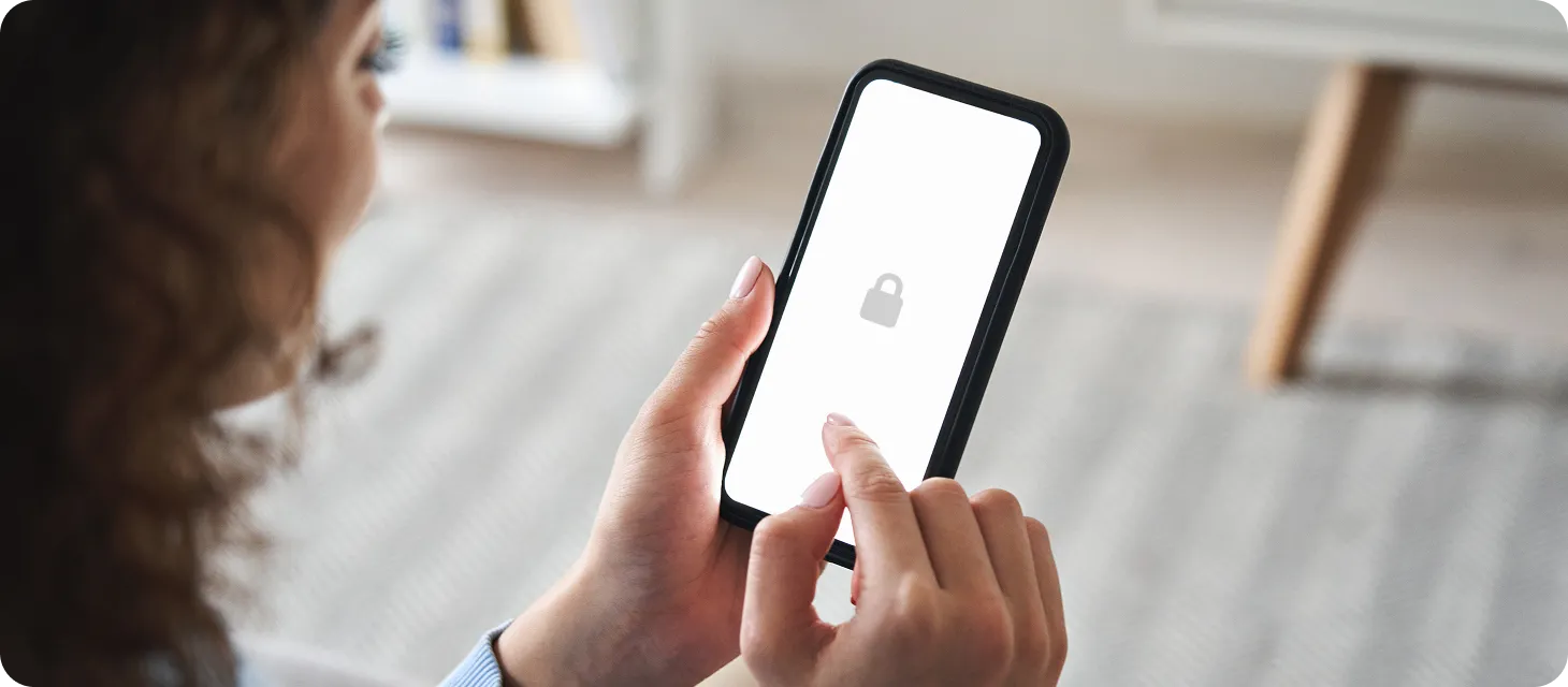 Person holding a smartphone with a white screen displaying a grey padlock icon, indicating a locked or secure state.