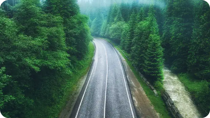 Group of six diverse friends laughing and embracing outdoors in bright sunlight.